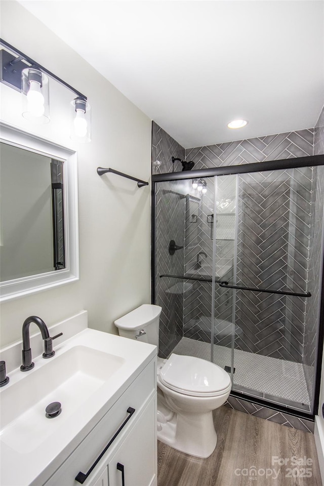 bathroom featuring hardwood / wood-style flooring, toilet, vanity, and walk in shower