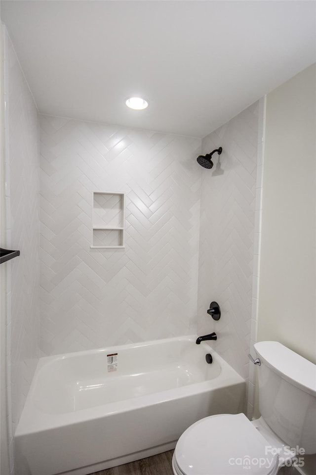 bathroom featuring wood-type flooring, toilet, and tiled shower / bath