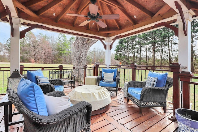 wooden deck featuring a gazebo, ceiling fan, outdoor lounge area, and a lawn