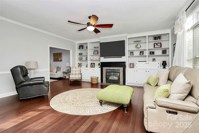 living room featuring wood-type flooring, ornamental molding, built in features, and ceiling fan