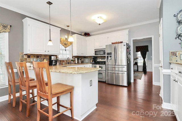 kitchen featuring pendant lighting, light stone countertops, stainless steel appliances, and white cabinets