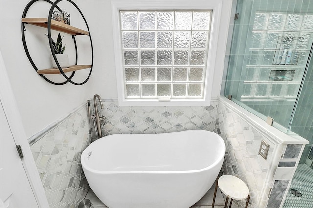 bathroom with a washtub and tile walls