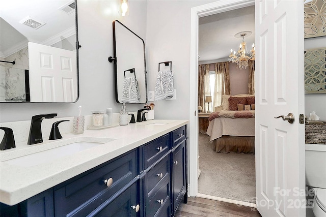 bathroom featuring toilet, a chandelier, ornamental molding, vanity, and hardwood / wood-style flooring