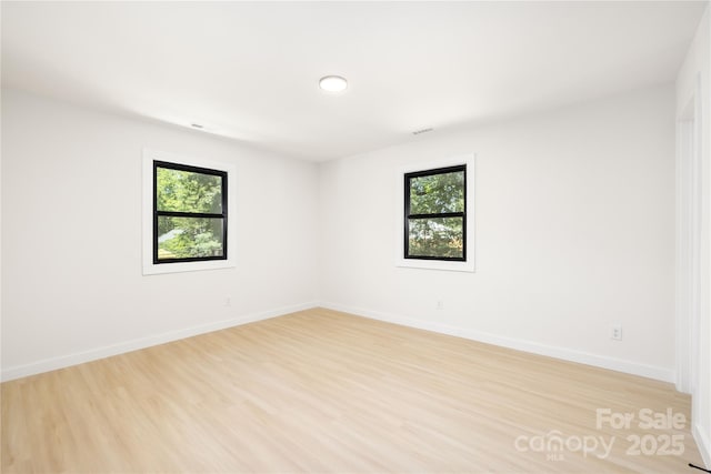 spare room featuring a wealth of natural light and light hardwood / wood-style flooring