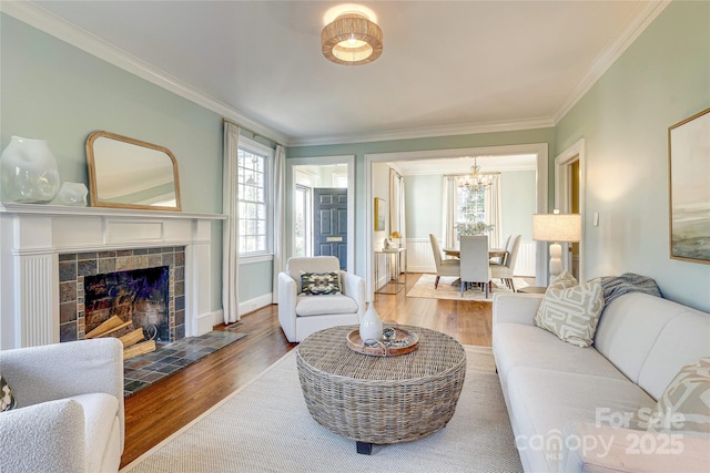 living room with hardwood / wood-style flooring, ornamental molding, and a tiled fireplace