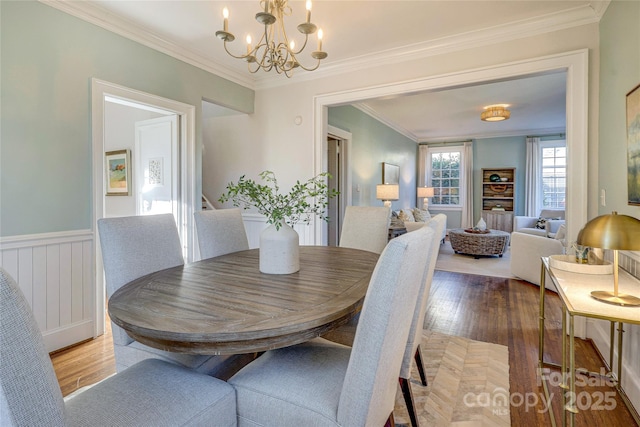 dining space featuring crown molding, wood-type flooring, and a notable chandelier