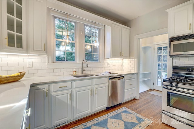 kitchen with light hardwood / wood-style floors, stainless steel appliances, backsplash, white cabinets, and sink