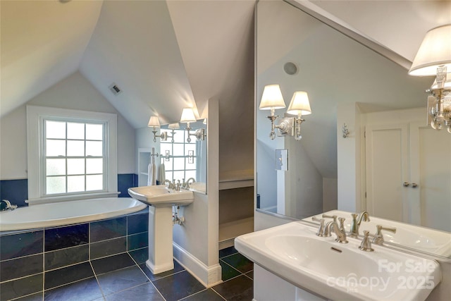 bathroom with vaulted ceiling, tiled tub, tile patterned floors, and dual sinks