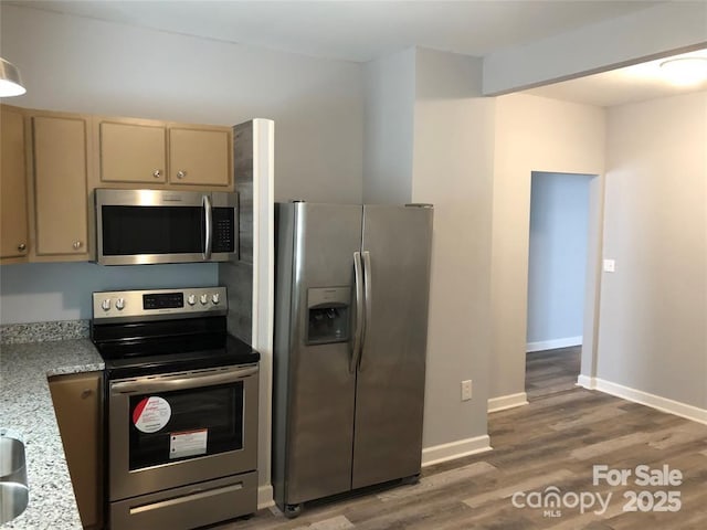 kitchen featuring dark wood-type flooring, stainless steel appliances, light brown cabinetry, and light stone counters