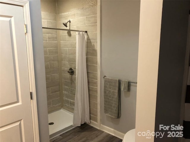 bathroom featuring wood-type flooring, toilet, and a shower with shower curtain