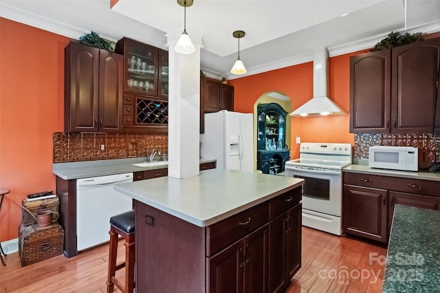 kitchen with pendant lighting, white appliances, wall chimney exhaust hood, tasteful backsplash, and light hardwood / wood-style flooring