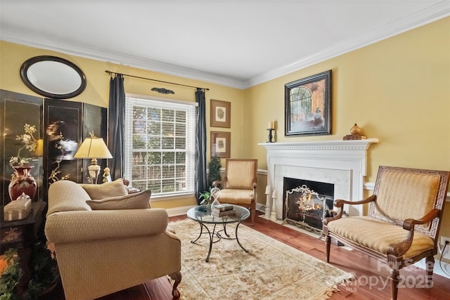 sitting room with hardwood / wood-style floors, crown molding, and a fireplace