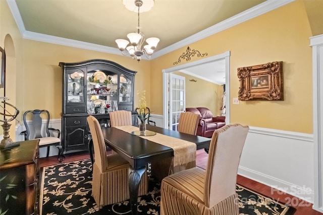 dining space featuring wood-type flooring, ornamental molding, and an inviting chandelier