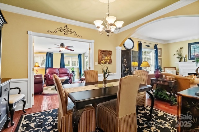 dining room with ceiling fan with notable chandelier, a wealth of natural light, dark hardwood / wood-style flooring, and ornamental molding