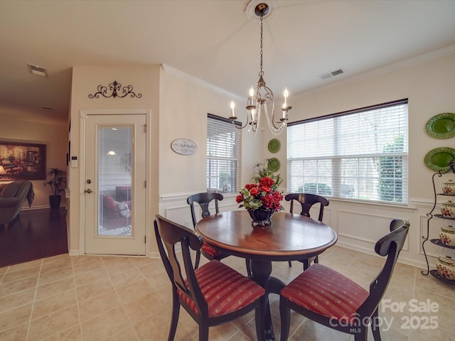 dining space featuring an inviting chandelier, ornamental molding, and light tile patterned flooring