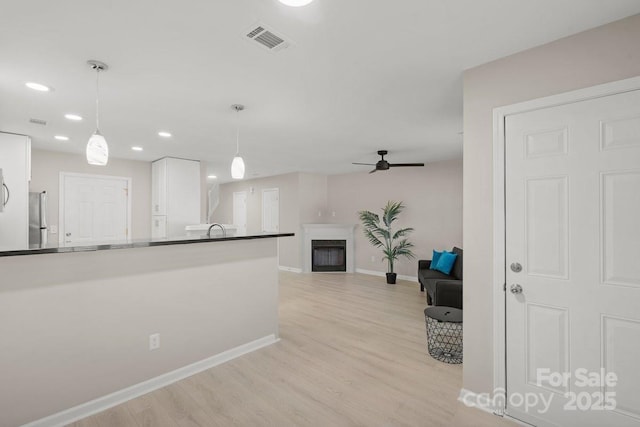 kitchen with pendant lighting, white cabinetry, stainless steel fridge, ceiling fan, and light hardwood / wood-style flooring