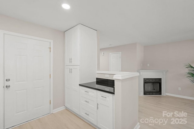 kitchen with kitchen peninsula, white cabinets, and light hardwood / wood-style floors