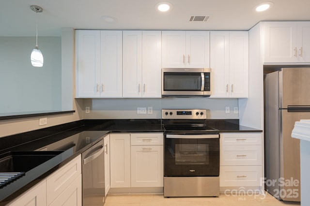 kitchen featuring decorative light fixtures, white cabinetry, stainless steel appliances, and dark stone countertops