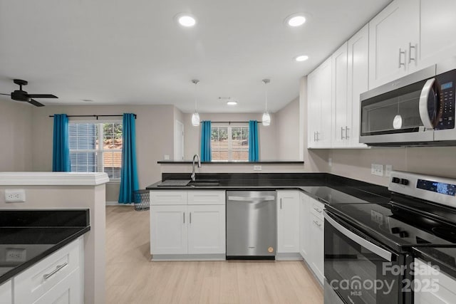 kitchen with decorative light fixtures, white cabinetry, appliances with stainless steel finishes, and kitchen peninsula