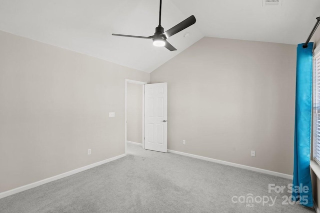 spare room featuring light carpet, vaulted ceiling, and ceiling fan