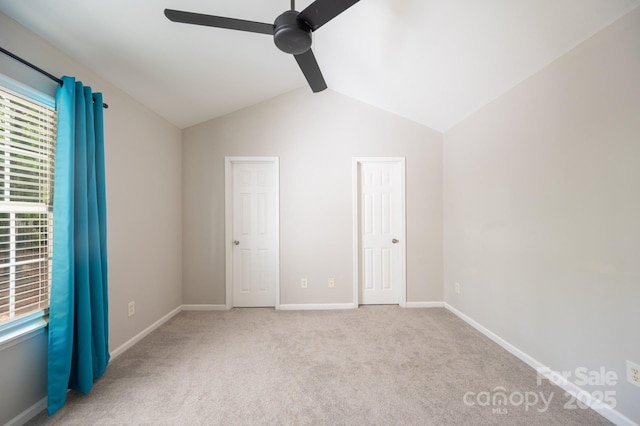 unfurnished bedroom featuring lofted ceiling, multiple windows, light colored carpet, and ceiling fan