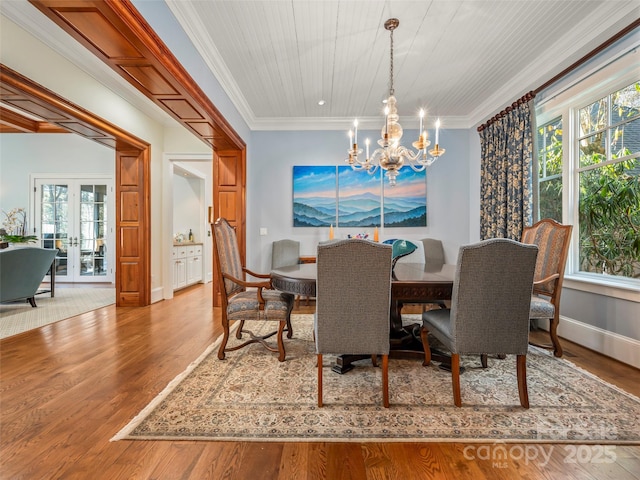 dining area with hardwood / wood-style flooring, ornamental molding, french doors, and an inviting chandelier