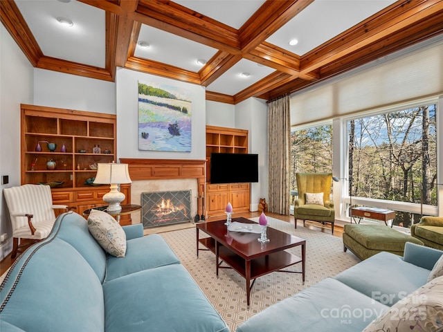 living room with beamed ceiling, built in features, ornamental molding, a tiled fireplace, and coffered ceiling