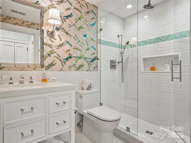 bathroom featuring toilet, vanity, tile walls, tile patterned flooring, and an enclosed shower