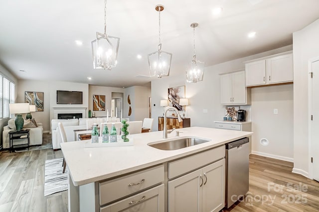 kitchen featuring dishwasher, sink, hanging light fixtures, an island with sink, and white cabinets