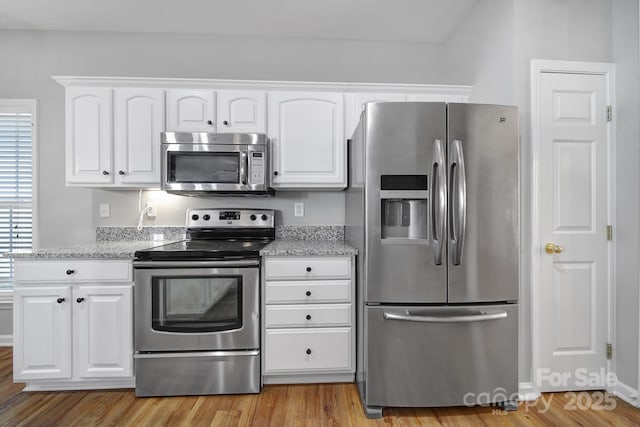 kitchen with stainless steel appliances, light wood-type flooring, light stone countertops, and white cabinets