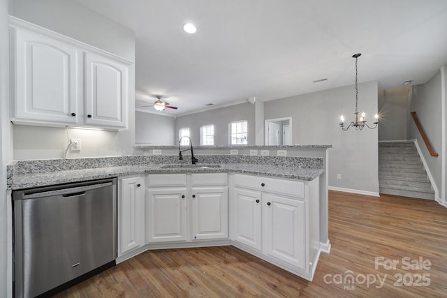 kitchen with pendant lighting, sink, dishwasher, white cabinetry, and light stone counters