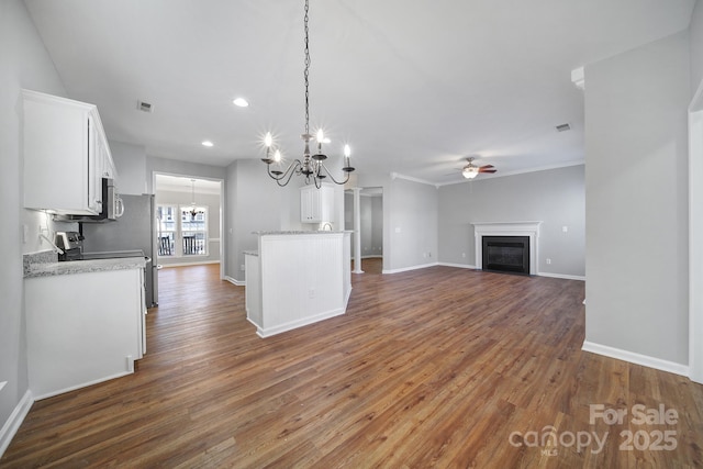 kitchen with dark wood-type flooring, white cabinetry, decorative light fixtures, ornamental molding, and ceiling fan with notable chandelier