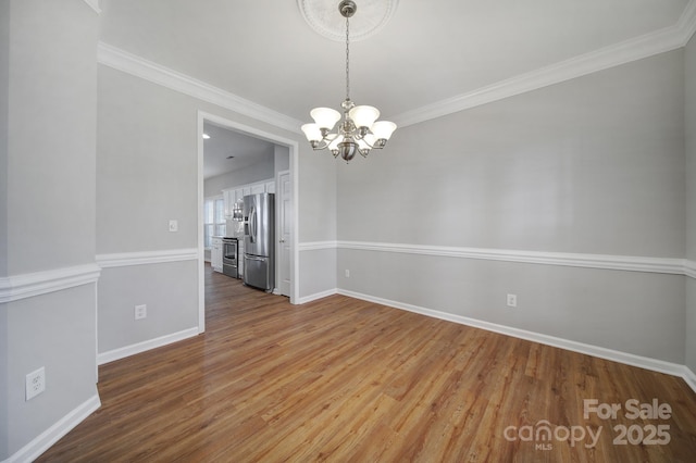 unfurnished dining area featuring an inviting chandelier, ornamental molding, and wood-type flooring