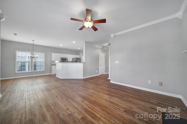 unfurnished living room featuring dark wood-type flooring, baseboards, and ceiling fan with notable chandelier