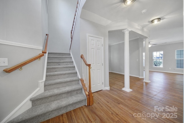 stairs featuring decorative columns, hardwood / wood-style floors, and ceiling fan