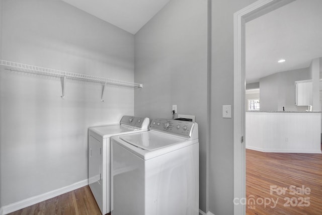 washroom with baseboards, laundry area, dark wood-type flooring, and washer and dryer