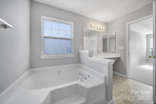 full bath with a garden tub and baseboards