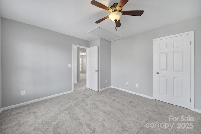 unfurnished bedroom featuring attic access, carpet floors, baseboards, and a ceiling fan