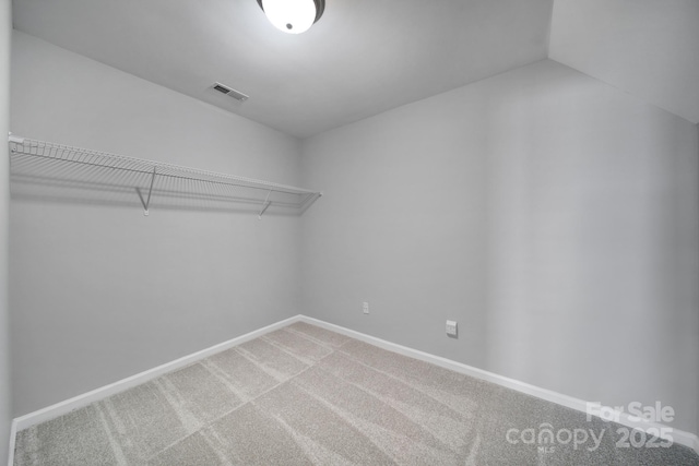 spacious closet featuring lofted ceiling, visible vents, and light carpet