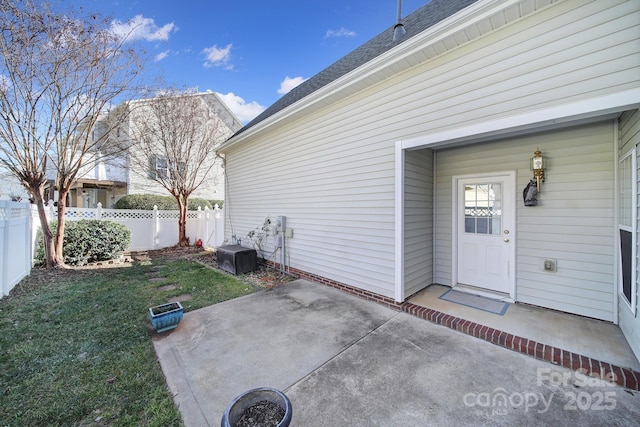 view of exterior entry with fence, a patio, and a yard