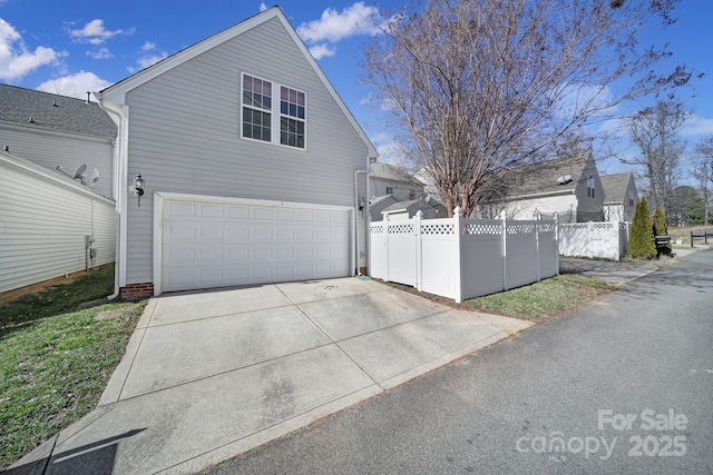 view of side of property featuring fence, driveway, and an attached garage