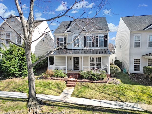 view of front of home featuring a standing seam roof, metal roof, a porch, and a front lawn