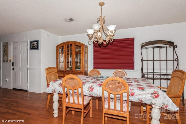 dining area featuring dark hardwood / wood-style flooring, a notable chandelier, and a textured ceiling