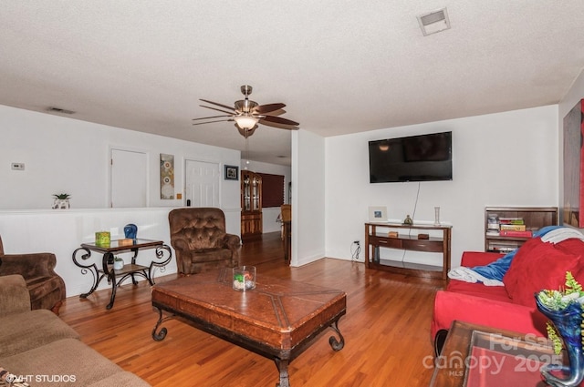 living room featuring ceiling fan, hardwood / wood-style floors, and a textured ceiling