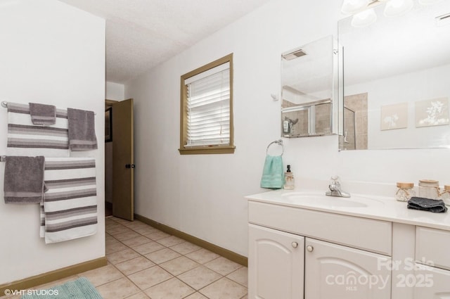 bathroom with tile patterned floors, a shower with door, vanity, and a textured ceiling