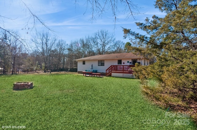 rear view of house with an outdoor fire pit, a yard, and a deck