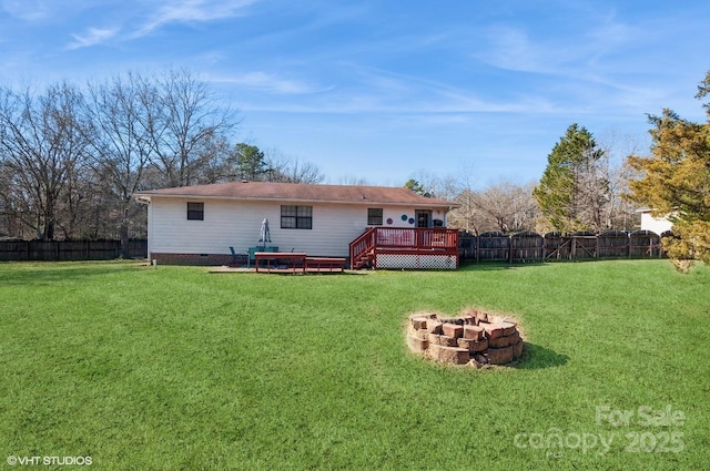 rear view of property with a deck, a fire pit, and a lawn