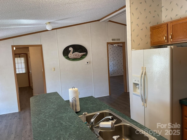 kitchen with lofted ceiling, sink, a textured ceiling, ornamental molding, and white refrigerator with ice dispenser