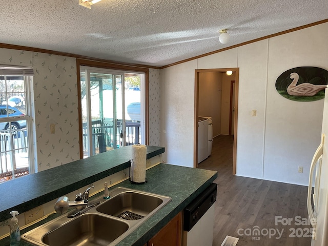 kitchen featuring washing machine and dryer, sink, dishwashing machine, and a textured ceiling