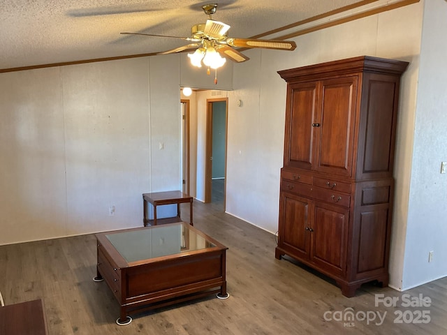 interior space featuring ceiling fan, crown molding, wood-type flooring, and a textured ceiling